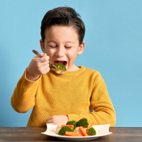 enfant mangeant ses légumes verts après les avoir saupoudré de MPP
